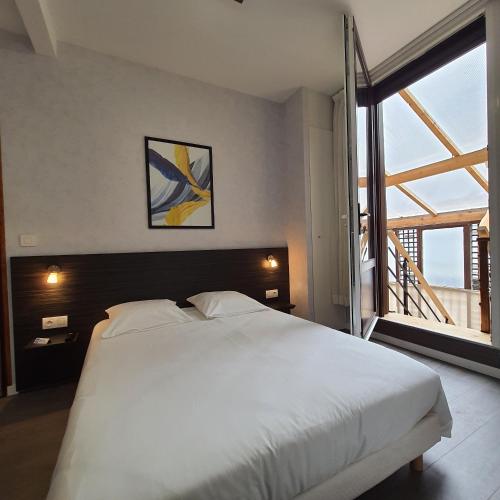 une chambre avec un lit blanc et une grande fenêtre dans l'établissement La Potinière Du Lac Appartements, à Bagnoles-de-l'Orne