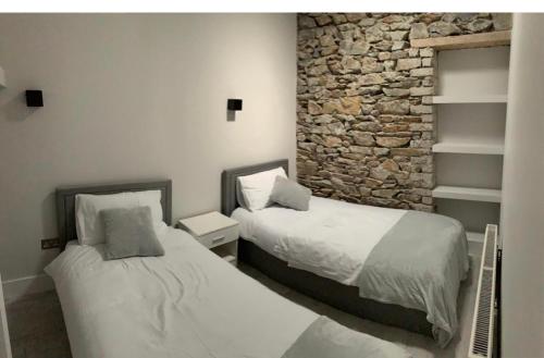 two beds in a room with a stone wall at Lisvarna House in Buncrana
