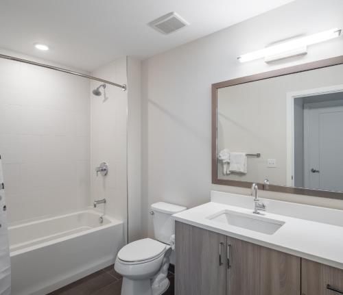 a bathroom with a toilet and a sink and a mirror at Global Luxury Suites at Bethesda Metro in Bethesda