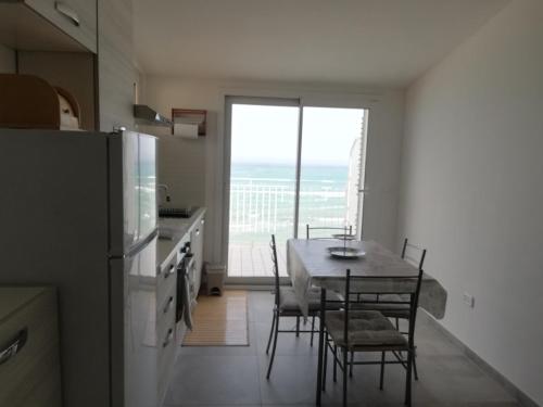 een keuken met een tafel met stoelen en een koelkast bij Attico fronte mare in Martinsicuro