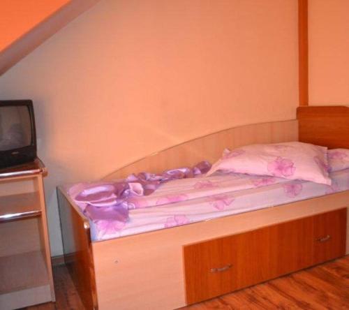 a bed with a dresser and a tv in a room at Pensiune Restaurant Brândușa in Suceava