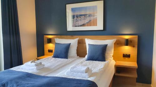 a bedroom with a bed with blue and white pillows at Willa Abrazja - wypoczynek dla dorosłych in Jastrzębia Góra