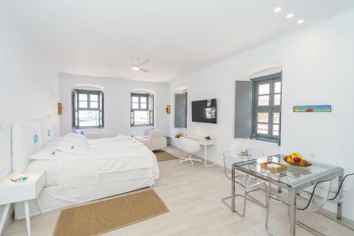 a white living room with a bed and a table at MyCrown Suite, Luxurious apartment with sea view located at the port of Hydra in Hydra