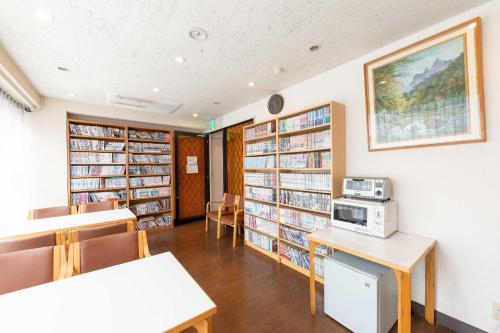 eine Bibliothek mit Bücherregalen und einer Mikrowelle in der Unterkunft Tabist Hotel Diana Yachiyodai in Ōwada