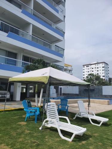 a group of lawn chairs and an umbrella at Tonsupa-Edificio MIRASOL in Tonsupa