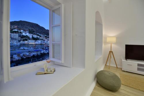 a living room with a large window and a chair at Hydra Hospitality Port Apartment in Hydra