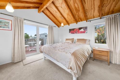 um quarto com uma cama e uma grande janela em Stroll to the Sea - Te Horo Beach Holiday House em Te Horo