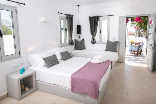 a white bedroom with two beds and a table at Sensia Luxury Apartment with Hot tub in Oia