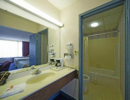 Express Airport Inn في ساندستون: حمام مع حوض ومرآة