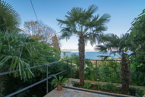 - une vue sur l'océan depuis un complexe avec des palmiers dans l'établissement Apartments and Rooms Vila Irma, à Opatija