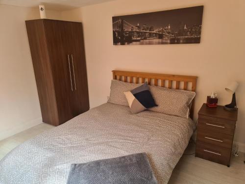 1 dormitorio con 1 cama con cabecero de madera y mesita de noche en Large Brick Chalet sleeps 6 mins to beach and amusements, en Leysdown-on-Sea