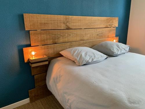 a bedroom with a bed with a wooden headboard and two pillows at Appartement T2 Lège Cap Ferret in Lège-Cap-Ferret