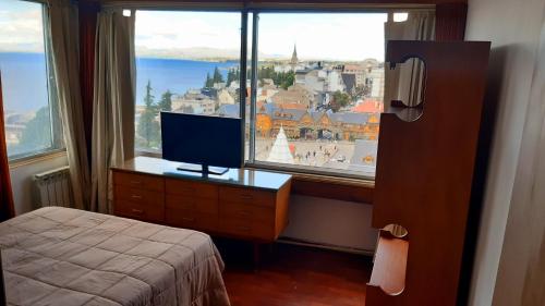 a bedroom with a bed and a window with a television at Lo de Ramón in San Carlos de Bariloche