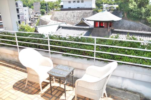 two chairs and a table on a balcony at Hotel Patio Dogo in Matsuyama