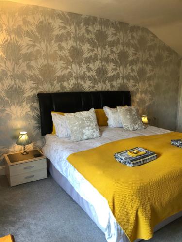 a bedroom with a large bed with a yellow blanket at Little Gem with Private Hot Tub - Up to 25 percent off ferry in Shanklin