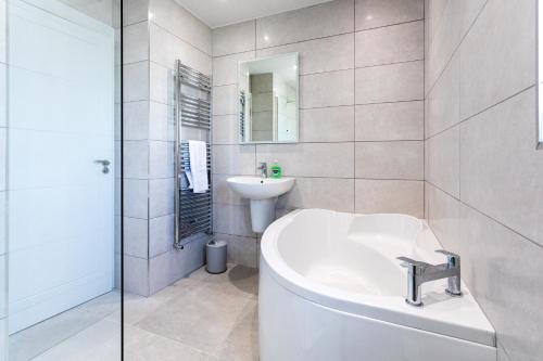 a white bathroom with a sink and a tub at Hilltown Lodge No3 in Hilltown