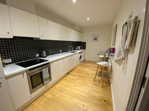 a kitchen with white cabinets and a wooden floor at Central, modern and peaceful, lovely Cathedral views, two-bed apartment with 40" smart TV & free onsite parking in Lincoln