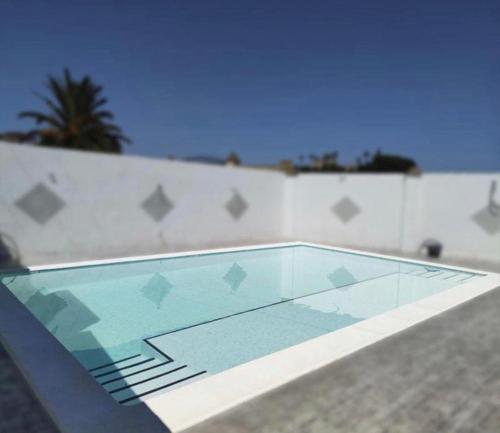 una piscina con una mesa de cristal frente a una pared en Casa Rural Finca Los Esterones, en Sanlúcar de Barrameda