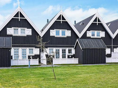 uma grande casa a preto e branco com uma árvore no quintal em 6 person holiday home in Nyk bing Sj em Rørvig