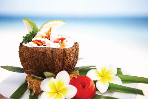 a drink in a coconut sitting on top of flowers at Castaway Island, Fiji in Castaway Island