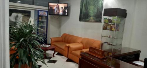 a living room with an orange couch in a room at Hotel Xilon Resort Plaza in Pasto