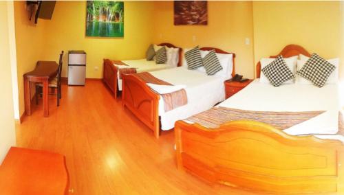 a room with three beds and a table and a chair at Hotel Xilon Resort Plaza in Pasto