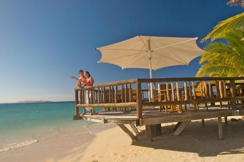 two people sitting on a bench on the beach with an umbrella at Castaway Island, Fiji in Castaway Island