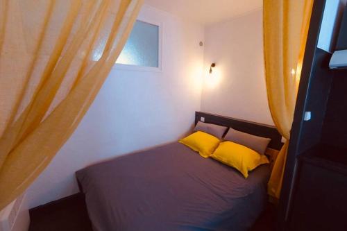 - une chambre avec un lit et 2 oreillers jaunes dans l'établissement Grand studio à deux pas du Vieux Port, à La Rochelle