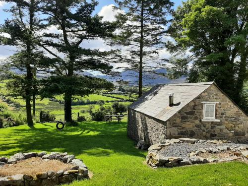 a stone building in a field with trees and grass at Drumena Cottage in Kilcoo