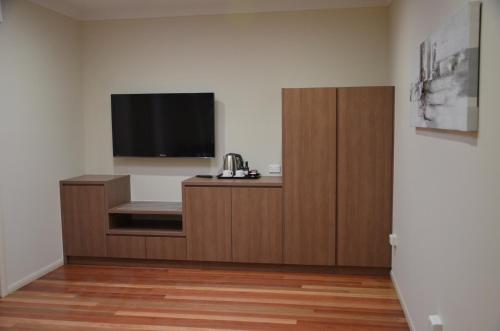 a room with a wooden floor and a white wall at The Australian Hotel Motel in Dalby