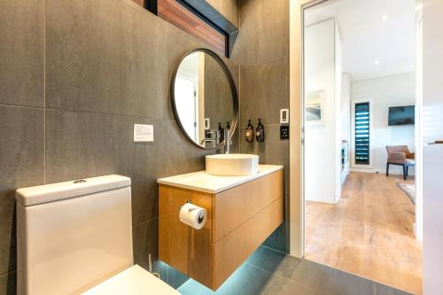 a bathroom with a toilet and a sink and a mirror at Moa 30 Runga - Waiheke Island in Oneroa