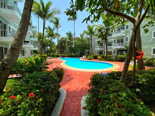 a swimming pool at a resort with palm trees and bushes at Punta Cana Blue Beach Estudio in Punta Cana