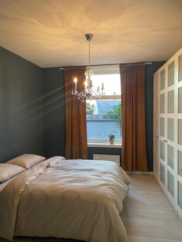 una camera con un letto, una finestra e un lampadario a braccio di City Center Apartment ad Ålesund