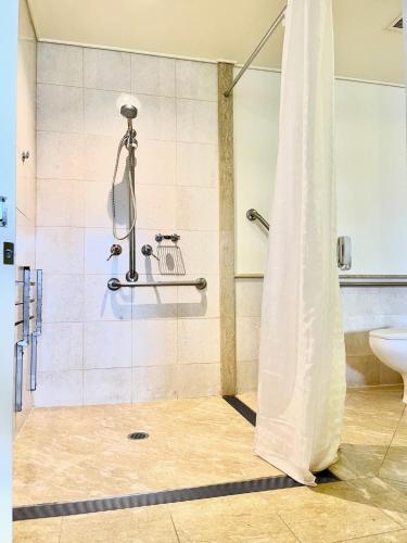 a bathroom with a shower with a toilet and a sink at Pullman Reef Hotel Casino in Cairns