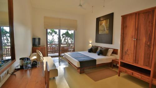 a bedroom with a bed and a table in a room at Pandanus Beach Resort & Spa in Bentota