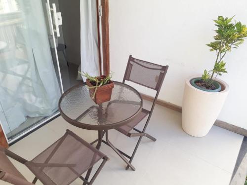 uma mesa de vidro e cadeiras numa varanda com plantas em Casa Jequitiba Quartos Mobiliados em Macaé