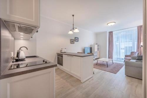 a kitchen with white cabinets and a living room at HaPPy Inn Rich Studio, Self Check-In-24x7,Parking-in-the-underground-Garage in Vilnius