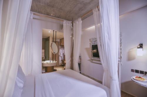 a white bathroom with a bed and a sink at Marc Hotel Gili Trawangan in Gili Trawangan