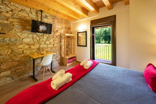 ein Schlafzimmer mit einem roten Bett und einer Steinmauer in der Unterkunft LA PANDELA in Las Herrerías