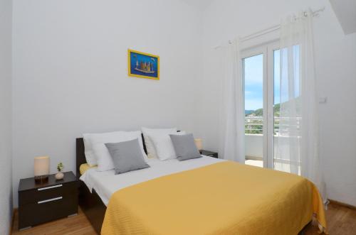 a white bedroom with a yellow bed and a window at Apartments Vrania in Seget Vranjica