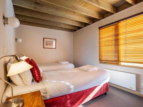 a bedroom with two beds and a table and a window at Banjo 4 Two Bedroom with Loft real fireplace and mountain views in Thredbo