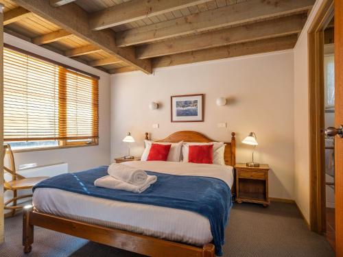 a bedroom with a large bed with red pillows at Banjo 4 Two Bedroom with Loft real fireplace and mountain views in Thredbo