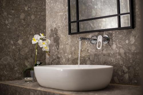 a white sink in a bathroom with a window and flowers at Dias Studios & Suites in Faliraki