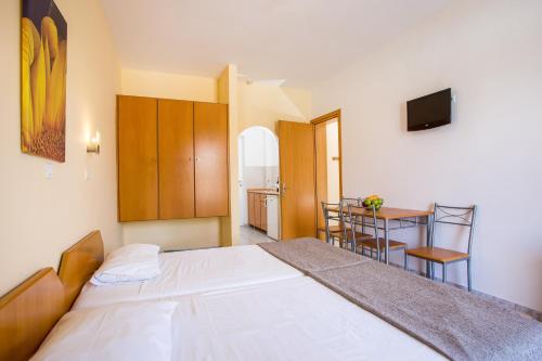 a bedroom with a white bed and a table with a chair at Dias Studios & Suites in Faliraki