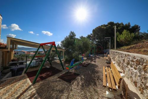 a playground with benches and a stone wall at Hotel Murter in Murter