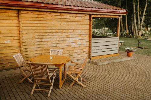 a wooden table and chairs in front of a cabin at Atpūtas kempings Usma in Usma