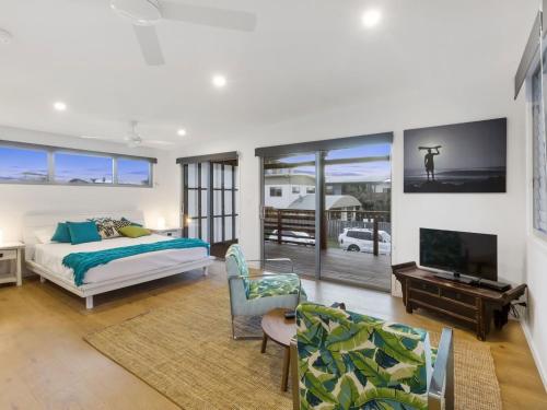 a bedroom with a bed and a living room with a tv at Beachfront Eclipse with Pool in Casuarina