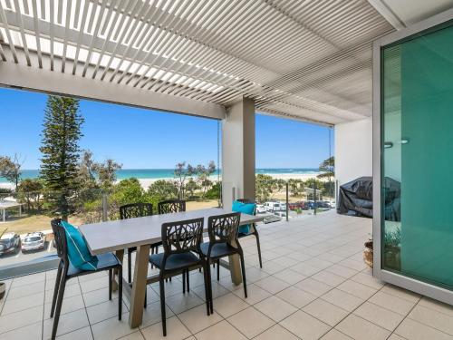 a patio with a table and chairs and a view of the ocean at Ocean Views at Nor Nor East 201 in Kingscliff