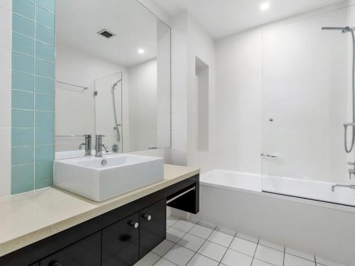 a white bathroom with a sink and a tub and a tubermott at Ocean Views at Nor Nor East 201 in Kingscliff