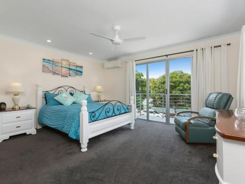 ein Schlafzimmer mit einem Bett und einem Stuhl in der Unterkunft Casuarina Dreaming Townhouse with Pool in Kingscliff